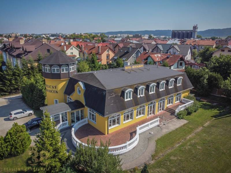 Yellow hotel with a tower, surrounded by a garden in the city of Poprad, hotels and guesthouses.