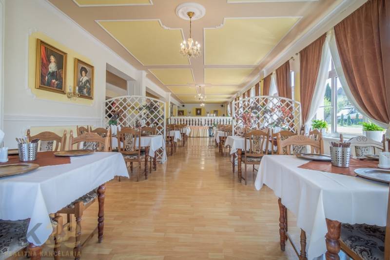 A hall with a wooden floor decor, set tables, and paintings on the walls. Hotels and guesthouses.