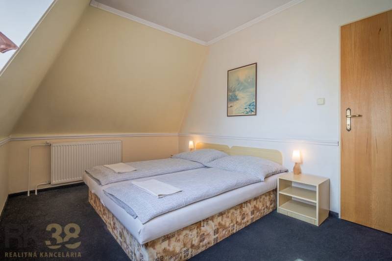 A room with a double bed, a nightstand, a painting, a lamp, carpets in hotels and guesthouses.