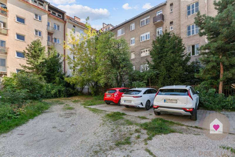 Parking lot with trees in front of a residential building on Vajnorská in Bratislava - Nové Mesto.