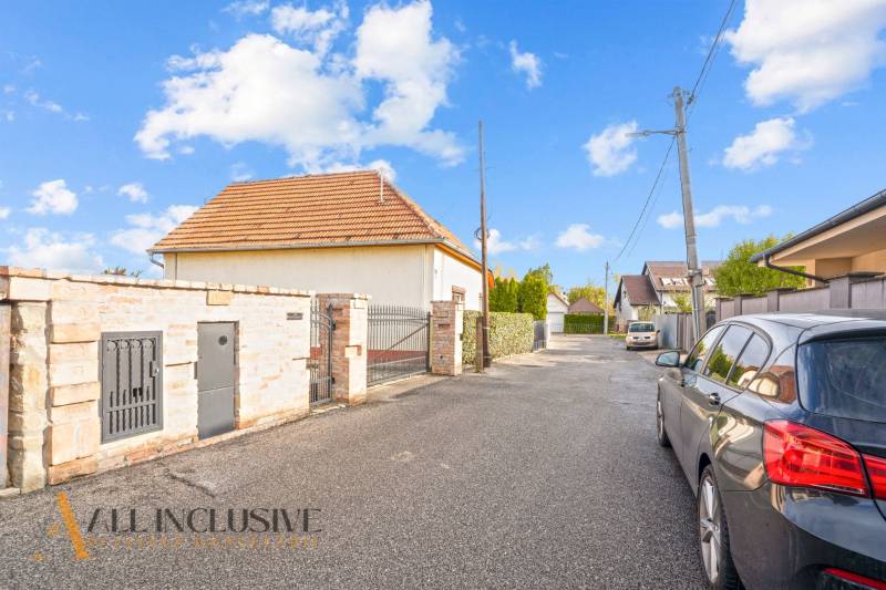 A family house on Kúpeľná Street in Dunajská Streda surrounded by cars and fencing.