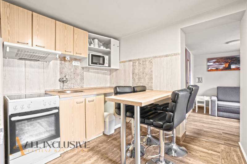 A kitchen in a family house with a bar table, black chairs, and a wooden decor floor.