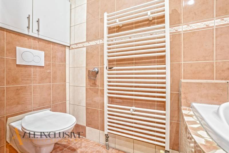 A bathroom in a family house with beige tiles and a ladder radiator.