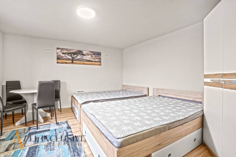 A bedroom in a family house with two beds, a wardrobe, and a wooden decor floor.