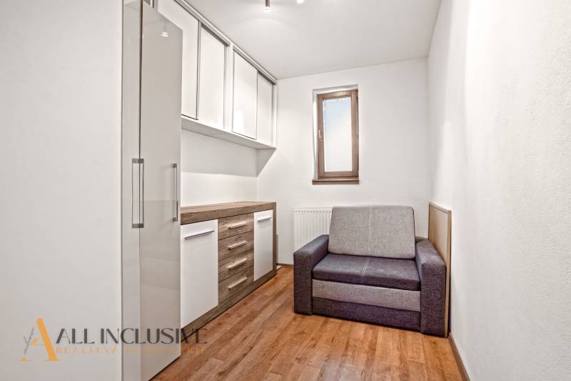 A room in a family house with a wooden decor floor, a gray sofa, and storage cabinets.