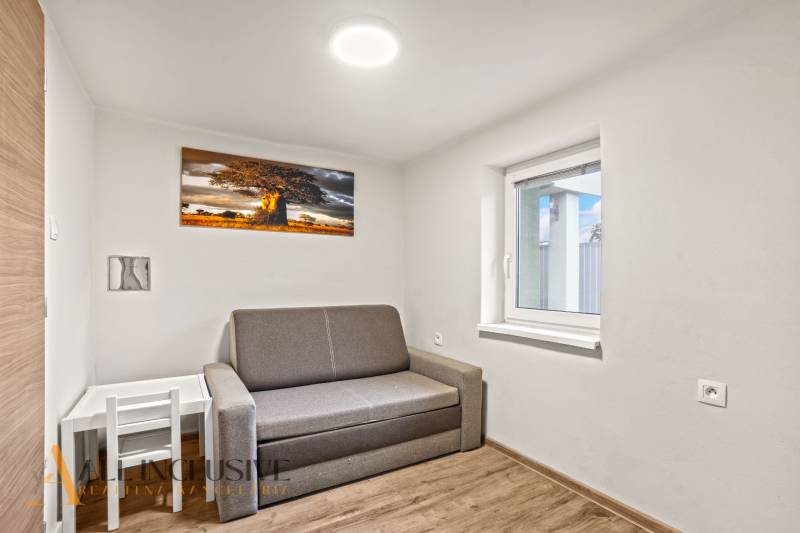 A room in a family house with a sofa, a picture of a tree, and a floor with a wooden decor.