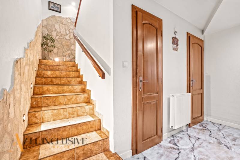 A staircase with a stone wall and tiles in a family house.
