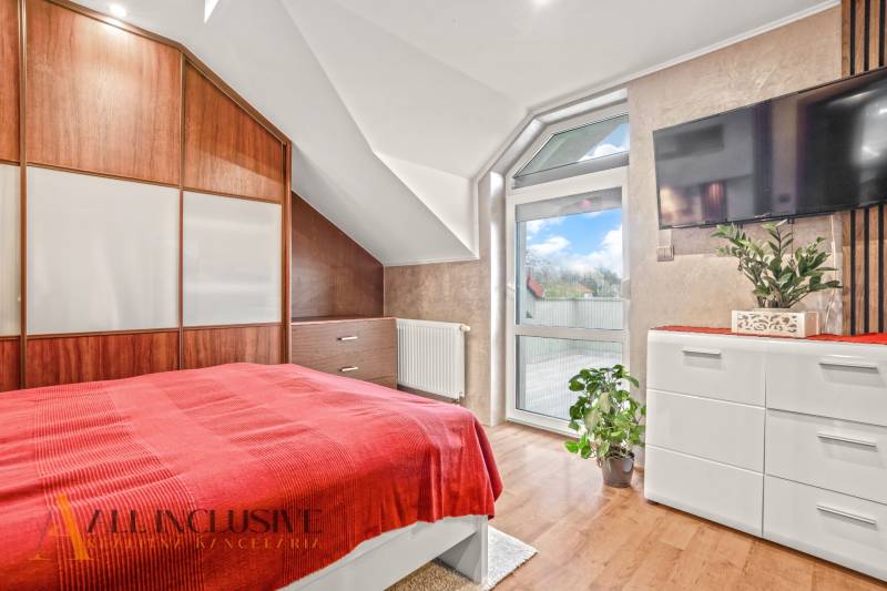 Bedroom in a family house with a bed, wardrobe, and wooden decor flooring.