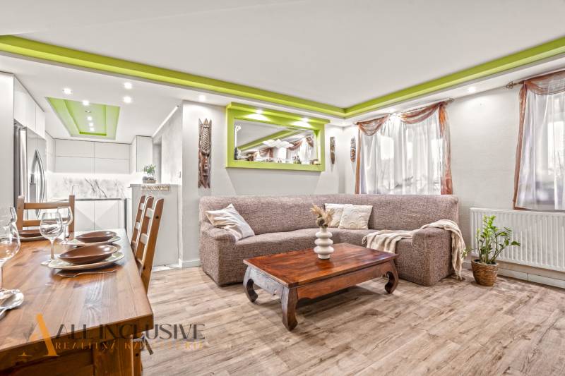 Living room in a family house with a wooden decor floor and green details on the ceiling.