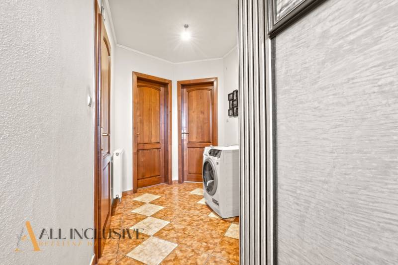 A hallway with a washing machine, a wooden decor floor, and wooden doors in a family house.