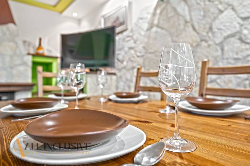 A dining table set in a family house with a wooden decor floor and a stone wall.