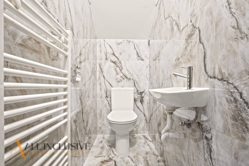 A toilet and a sink in a family house lined with gray marble tiles.