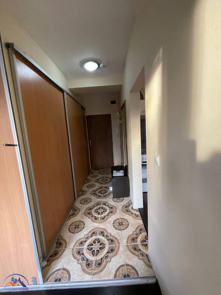 A narrow hallway in a one-room apartment with distinctive tiles and sliding wardrobes.