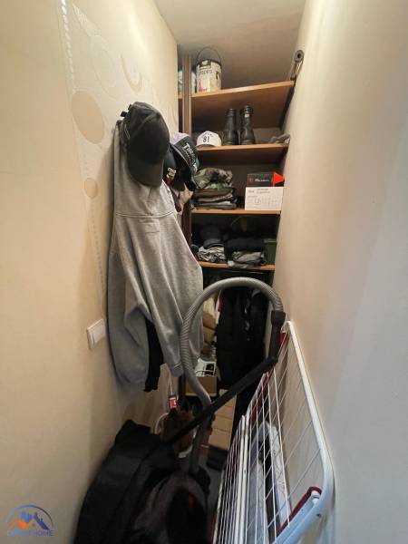 Storage space with clothing, hats, shoes, and a vacuum cleaner in a studio apartment.