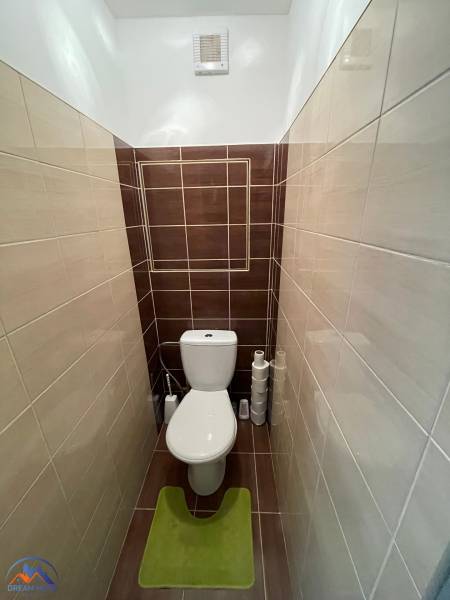 Bathroom section of a studio apartment with stylish tiles and a toilet.
