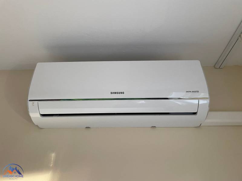 The air conditioning on the wall is part of the equipment of a studio apartment.