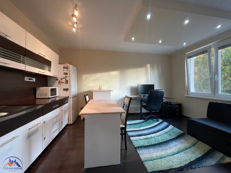 A kitchen in a studio apartment with a wood-patterned floor and a work corner.