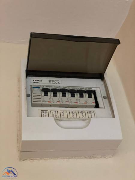 An electrical panel with an open cover and labeled circuit breakers in a studio apartment.