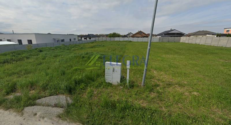 Green building plot bordered by a fence in the Čaňa area suitable for residential use.