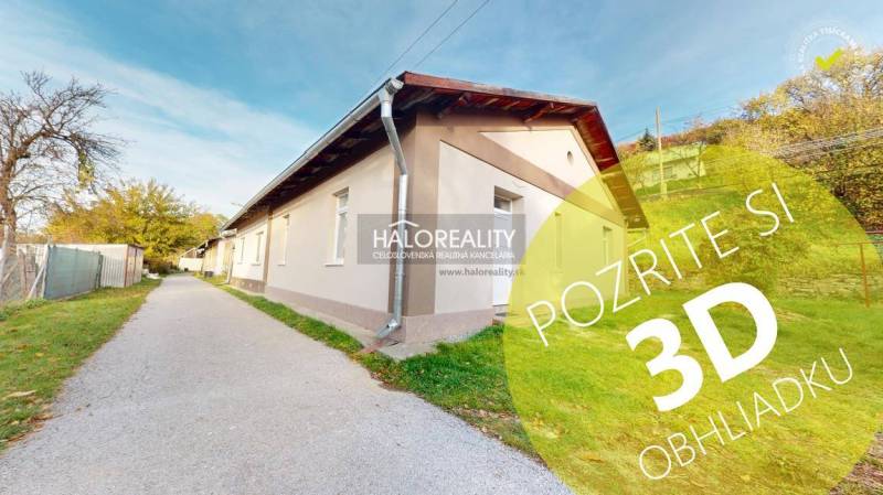 A family house in Sirk with a long facade, green lawn, and an access road on the side.