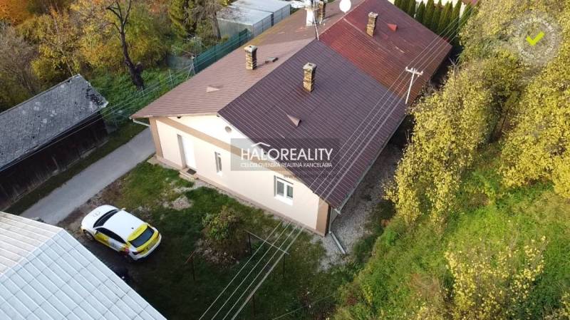 A family house in Sirk with a metal roof and a car on the grassy garden.