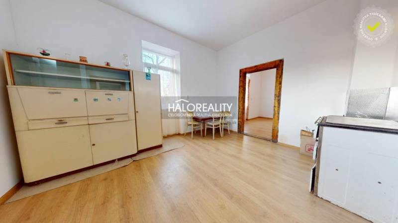 Interior of a family house with a wooden decor floor, a cabinet, and a table with two chairs.