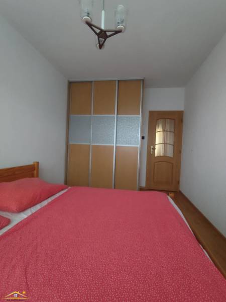 A bedroom in a 3-room apartment with a bed and a wardrobe with sliding doors.