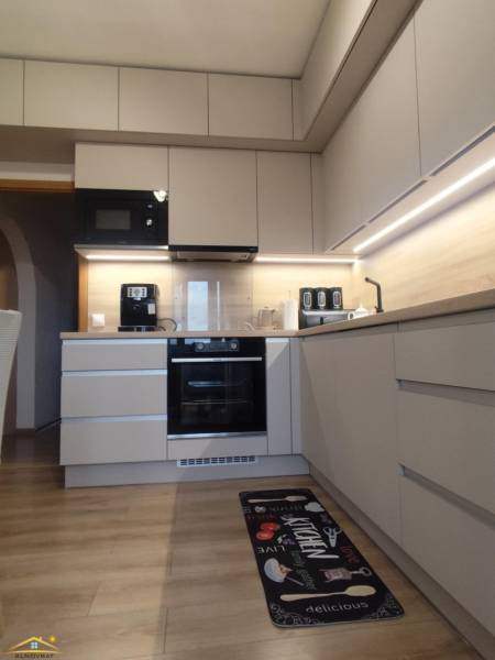 A kitchen in a 3-room apartment with a wooden decor floor and built-in appliances.