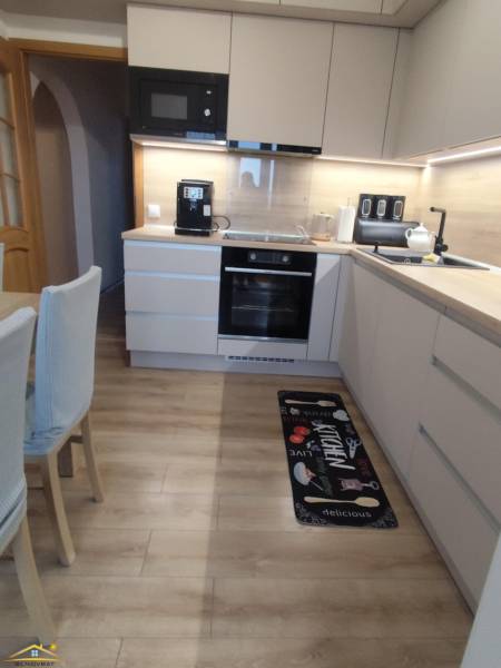 A kitchen with a wood-patterned floor in a 3-room apartment, featuring modern equipment and decor.