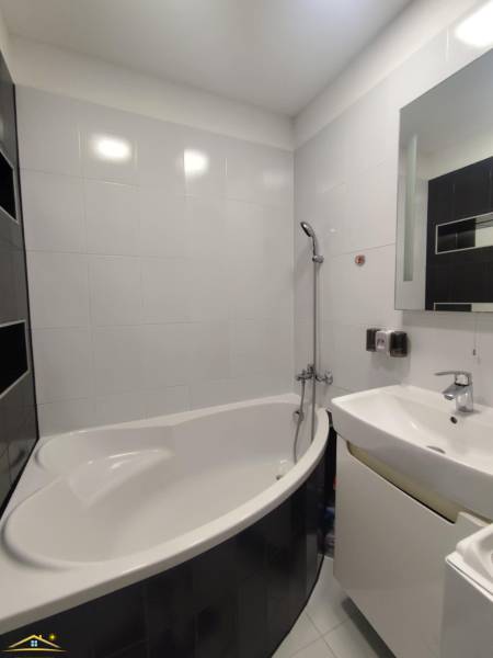 A bathroom of a 3-room apartment with a shower, a bathtub, and white tiles.