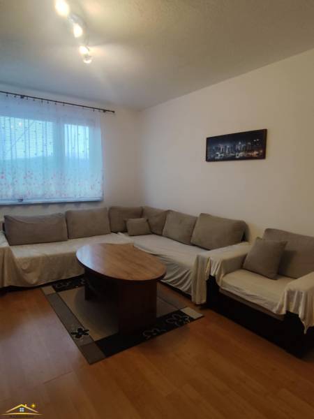 Living room in a three-room apartment with a corner sofa, wooden decor flooring, coffee table.