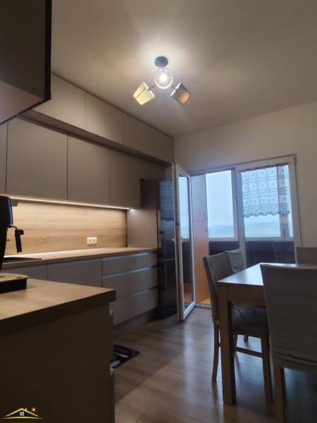 A kitchen with a wooden decor floor and a dining table in a 3-room apartment.