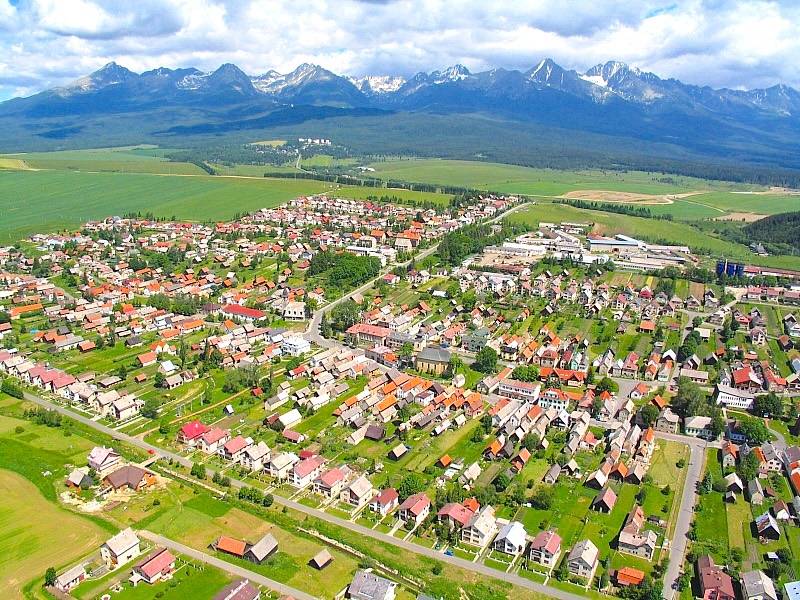 Aerial view of agricultural and forest land in Štrba with the High Tatras in the background.
