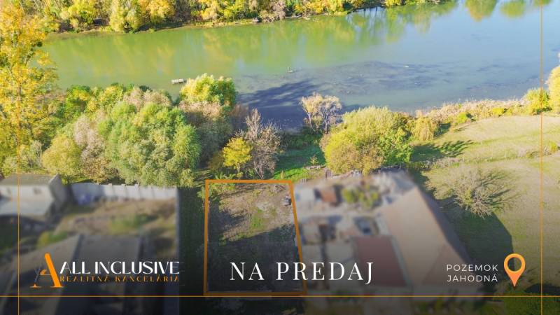 Land for sale by the river in Jahodná, surrounded by greenery and trees.