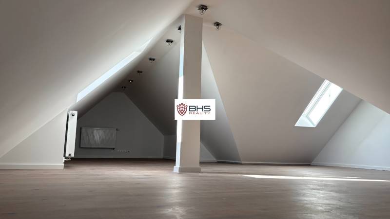 Attic space in a 3-room apartment with a window and a floor with a wooden decor.