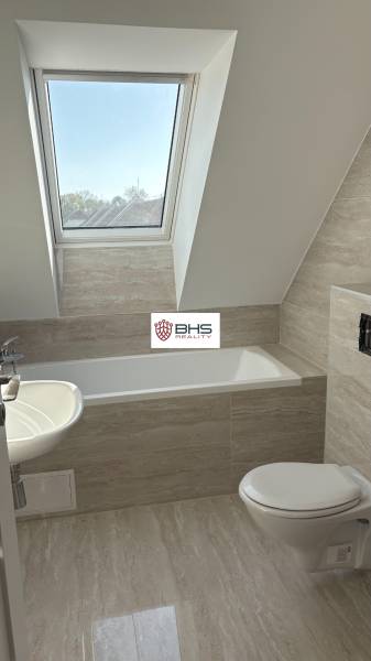 A bathroom in a 3-room apartment with a bathtub and a skylight, flooring with a wood decor.