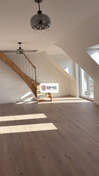 Attic space in a 3-room apartment with a wooden decor floor and a staircase.