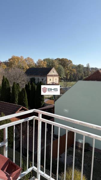 The view from the 3-room apartment in Tomášikovo shows gardens and an old building.