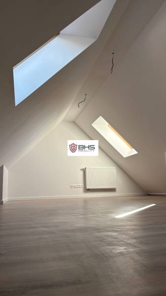 Attic room with wood-patterned flooring and skylights in a 3-room apartment.