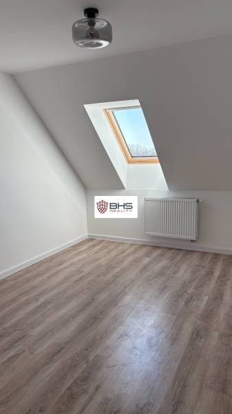 Attic room with a wooden decor floor and a skylight in a 3-room apartment.