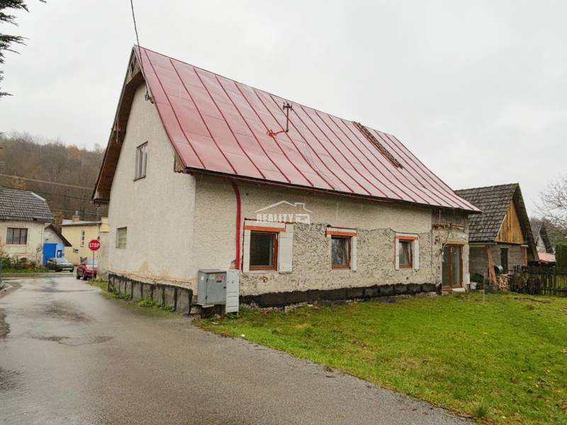 A family house in Kolárovice with a red roof by the road and a green lawn.