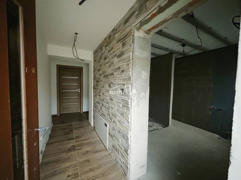 A hallway with a stone-decorated wall and a wood-decorated floor in a family house.