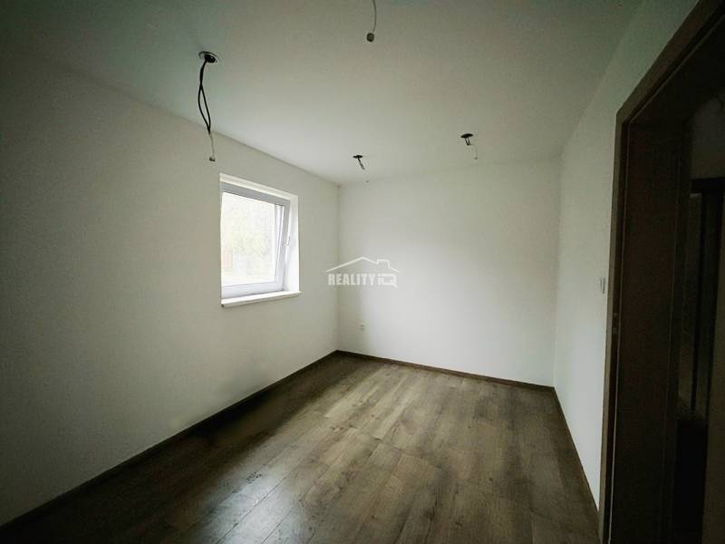 A room in a family house with white walls and a wooden decor floor.