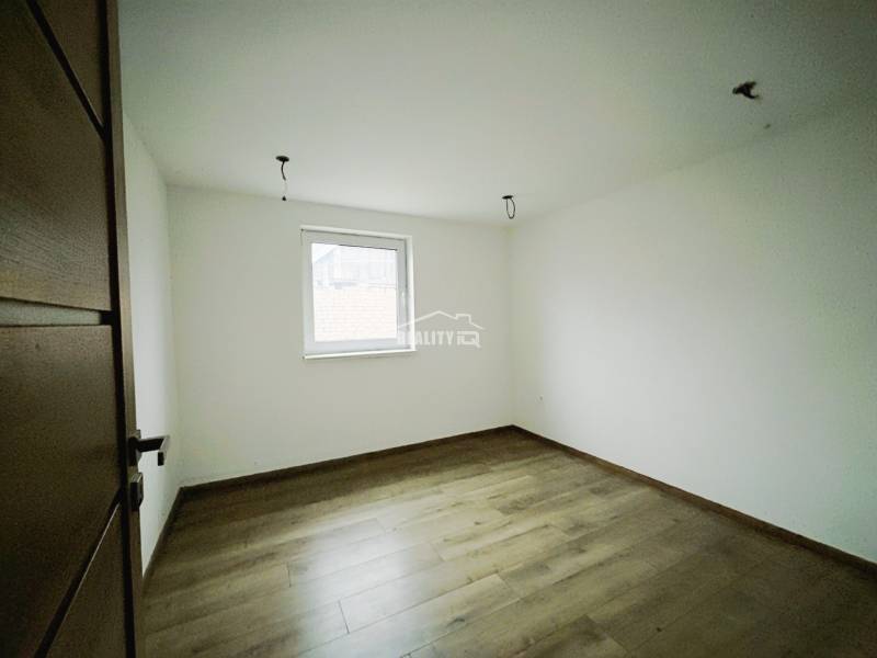 A room in a family house with white walls and a wooden decor floor.