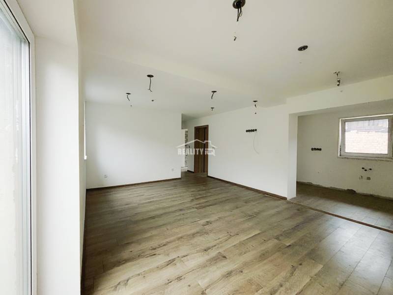 A spacious room in a family house with a wooden decor floor and white walls.