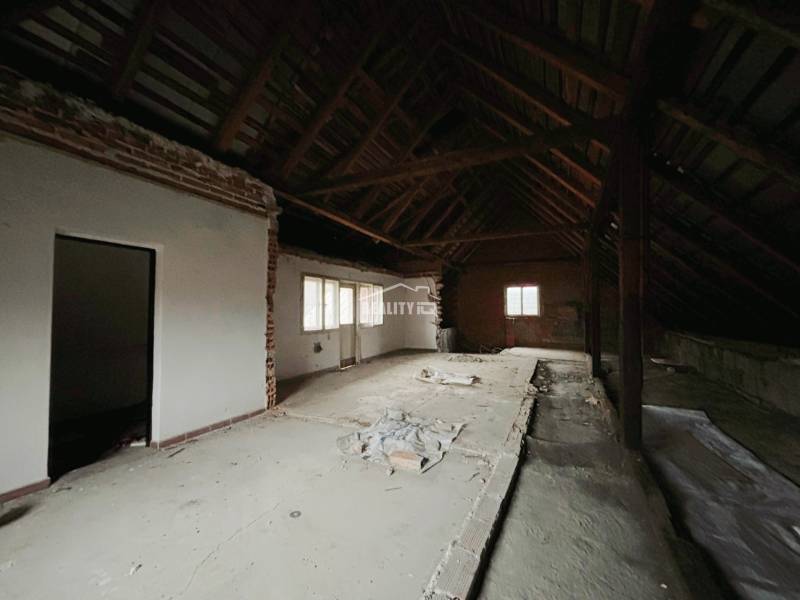 Attic space of a family house with exposed roof structure and white walls.