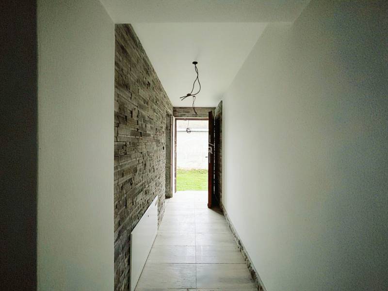 A hallway of a family house with stone cladding and a view of the garden.