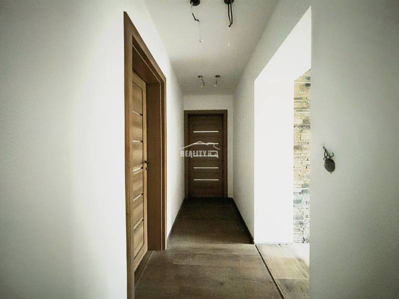 A hallway in a family house with doors in a wooden decor and white walls.