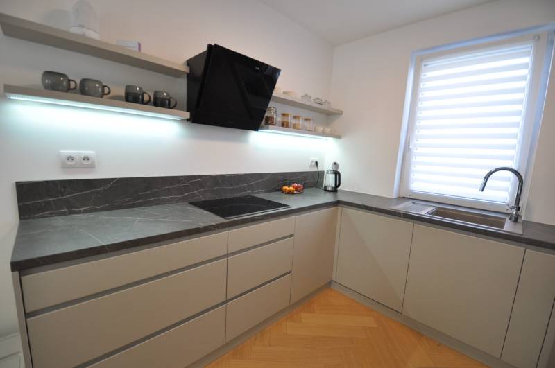A kitchen in a family house with a dark countertop and a floor with a wood decor.