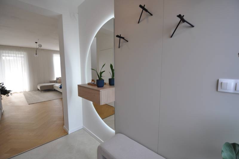 Interior of a family house with a wooden decor floor, a mirror, and houseplants.